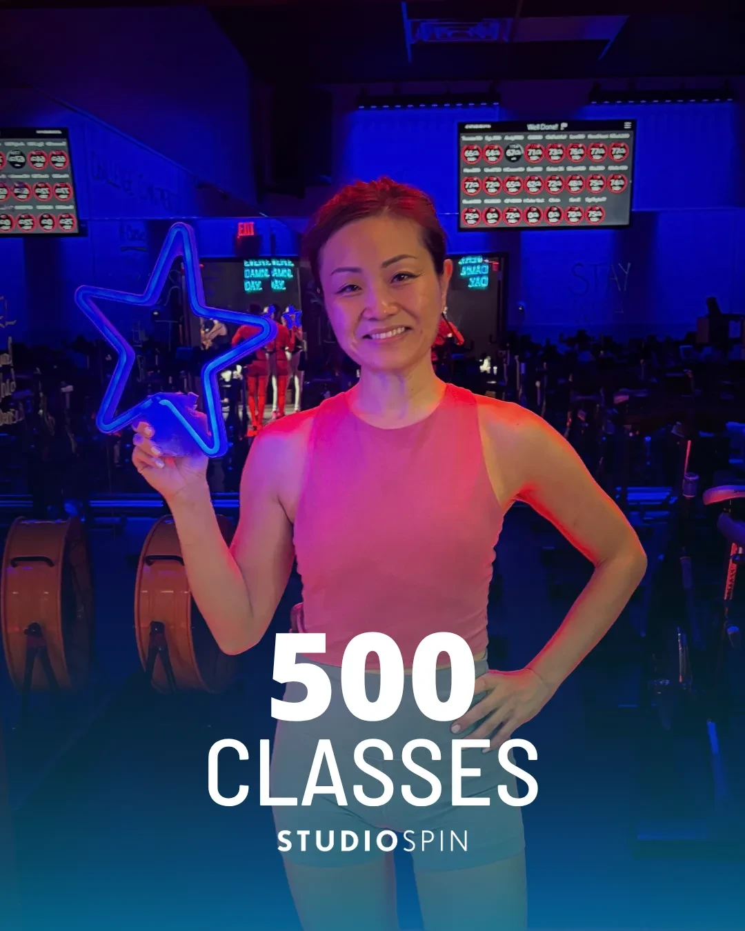 A Studio Spin member celebrating 500 classes under the Every Damn Day neon sign.