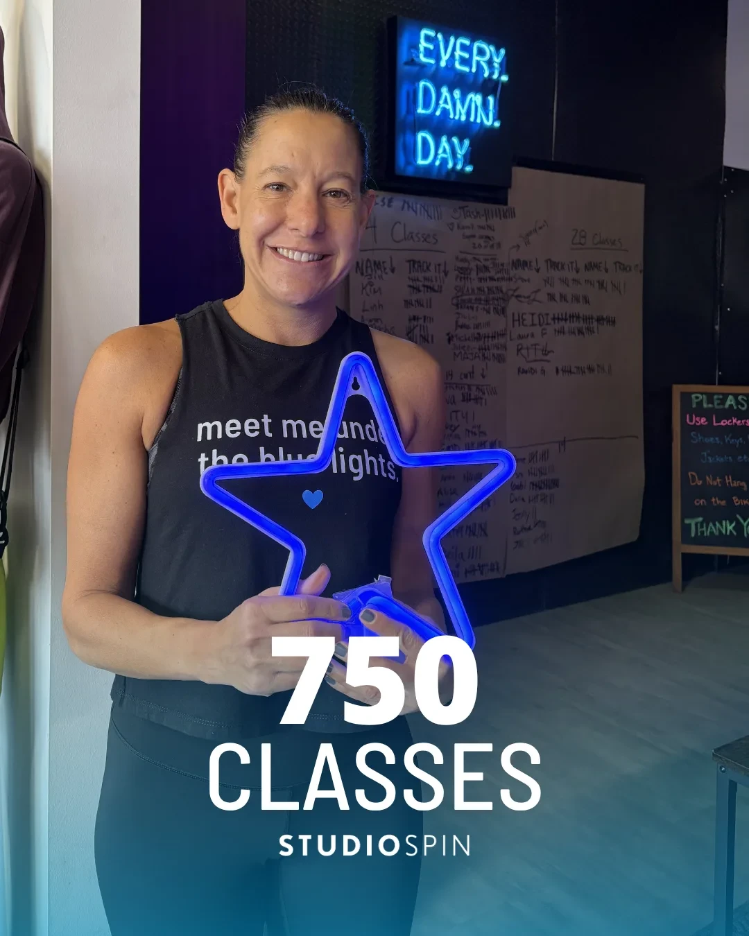 A Studio Spin member celebrating 750 classes under the Every Damn Day neon sign.